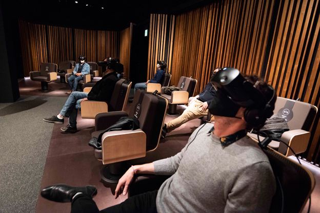Audience seated in rows of armchairs, wearing VR headsets during Symphony